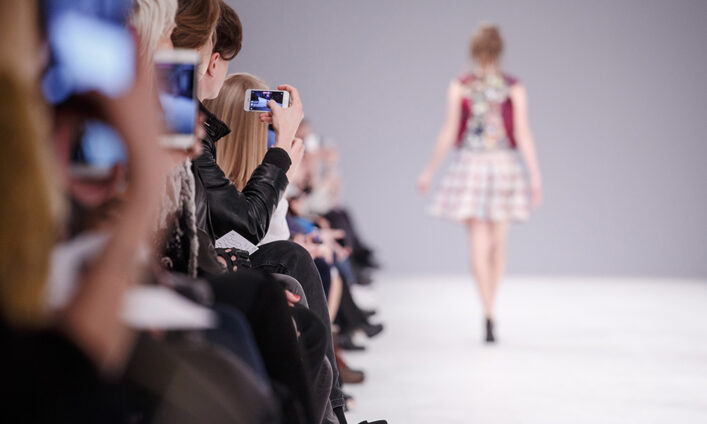 A woman taking a picture of a fashion show